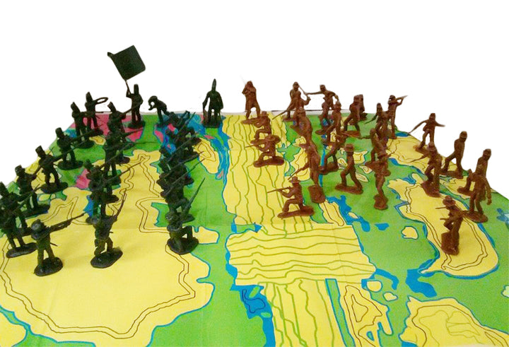 Alamo Toy Soldiers—green and brown PVC figures—are arranged on a raised, colorful map, positioned to face each other in a battle scenario on the map’s surface.