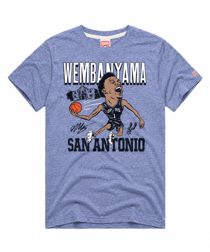Show off your Spurs pride with the San Antonio Spurs Victor Wembanyama T-Shirt, showcasing a blue design with a cartoon basketball player in a San Antonio Spurs jersey holding a ball. The shirt features “WEMBANYAMA SAN ANTONIO” text and stylized signatures underneath—perfect for any Victor Wembanyama fan in the Alamo City.