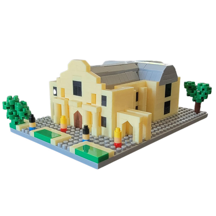 Build your own Mini Alamo with this compact building block set featuring a yellow structure, brown door, black windows, gray roof, green trees, and baseplate—ideal for fans seeking assembly instructions or inspiration.