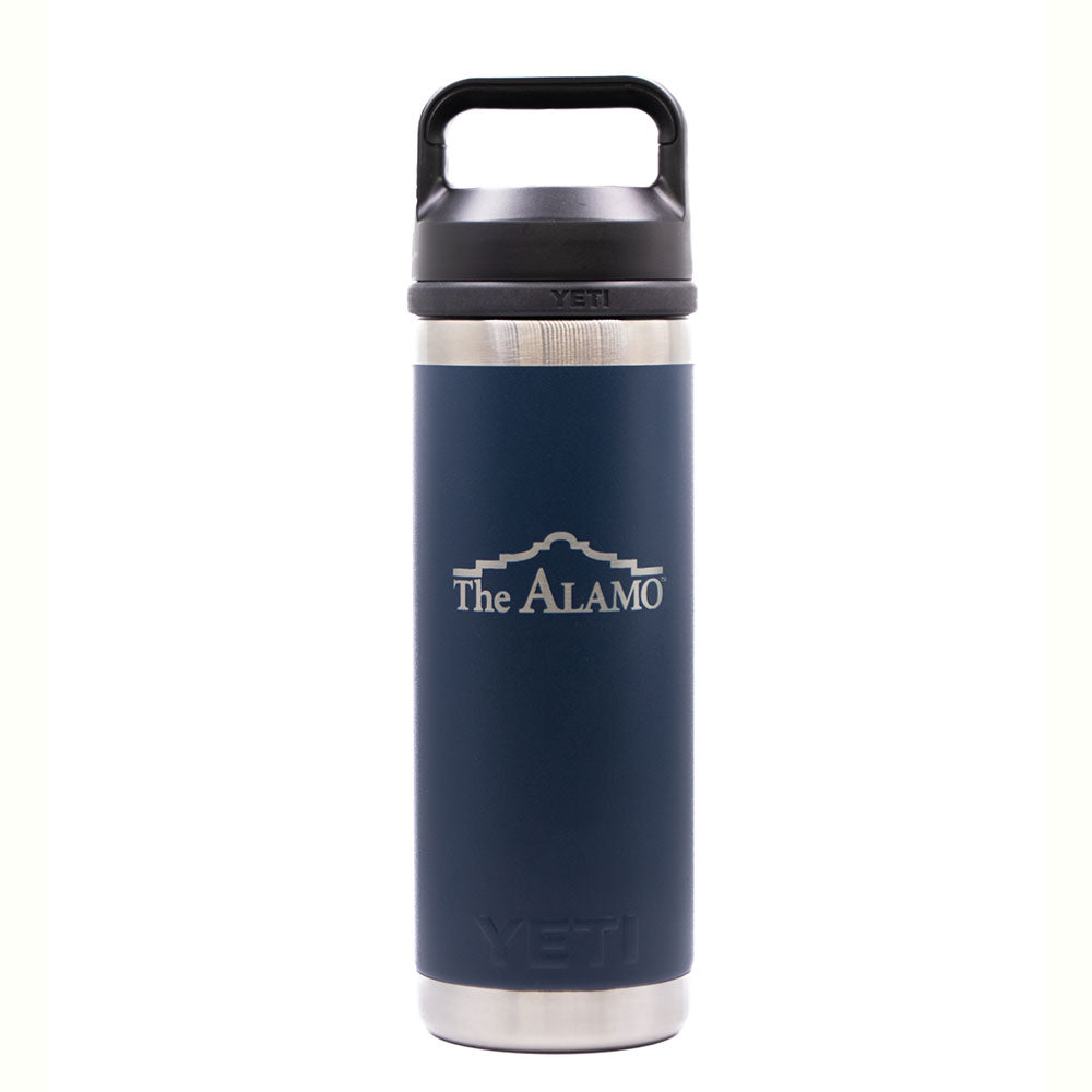 The Alamo YETI Rambler Bottle - 18 oz. is a navy blue and silver leakproof stainless steel bottle with a black handle, featuring the Alamo logo in white beneath an outline of the Alamo mission.