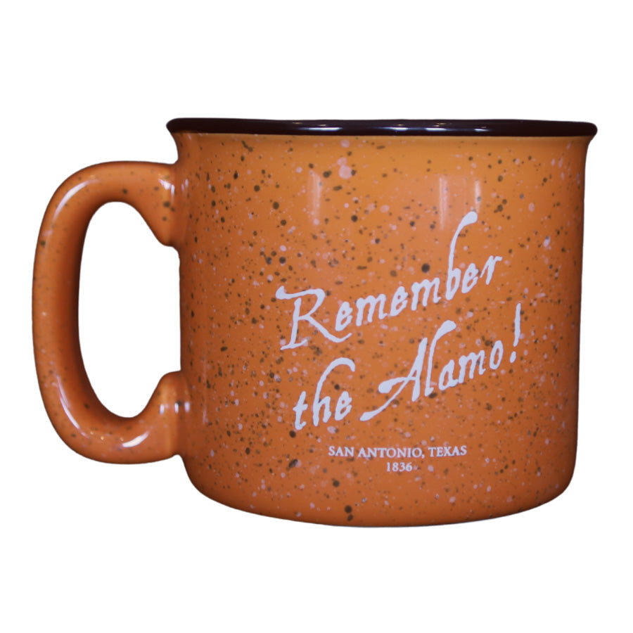 The Alamo Orange Mug is a terracotta speckled coffee mug with a black rim, featuring white text that reads "Remember the Alamo!" and smaller text below saying "San Antonio, Texas 1836.